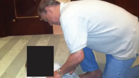 Image described by the BBC as appearing to show a man believed to be Prince Andrew kneeling over a fully clothed woman, touching her stomach.
