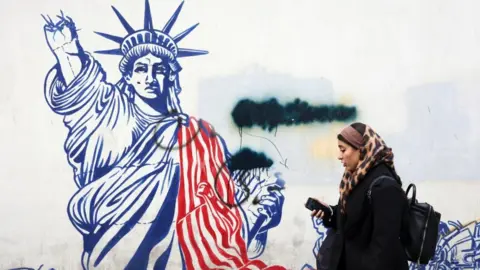 An Iranian woman walks past an anti-US mural in Tehran depicting the Statue of Liberty.