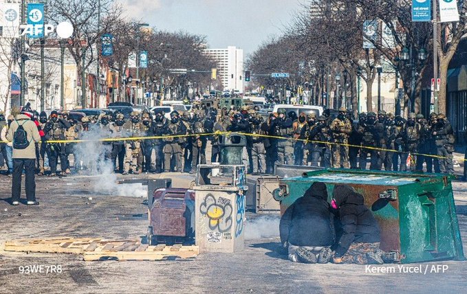 Federal immigration agents and police at the Minneapolis scene following the shooting of 37-year-old Alex Pretti, with unrest nearby.