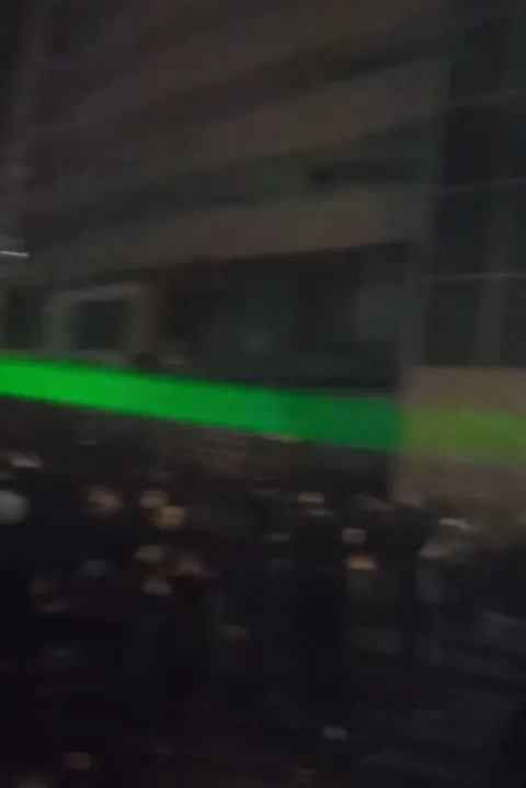 A green laser is pointed across a large crowd of protesters in Tehran