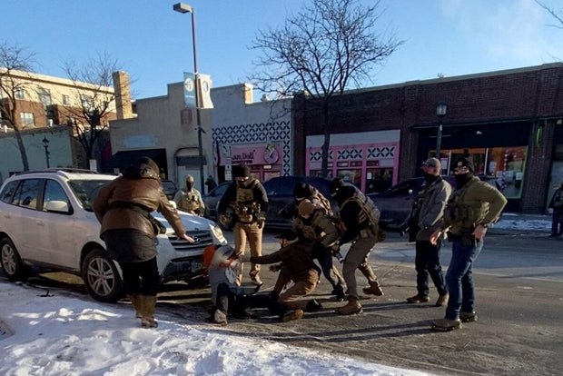 A federal officer pins Alex Pretti to the ground as others gather moments before the shooting.