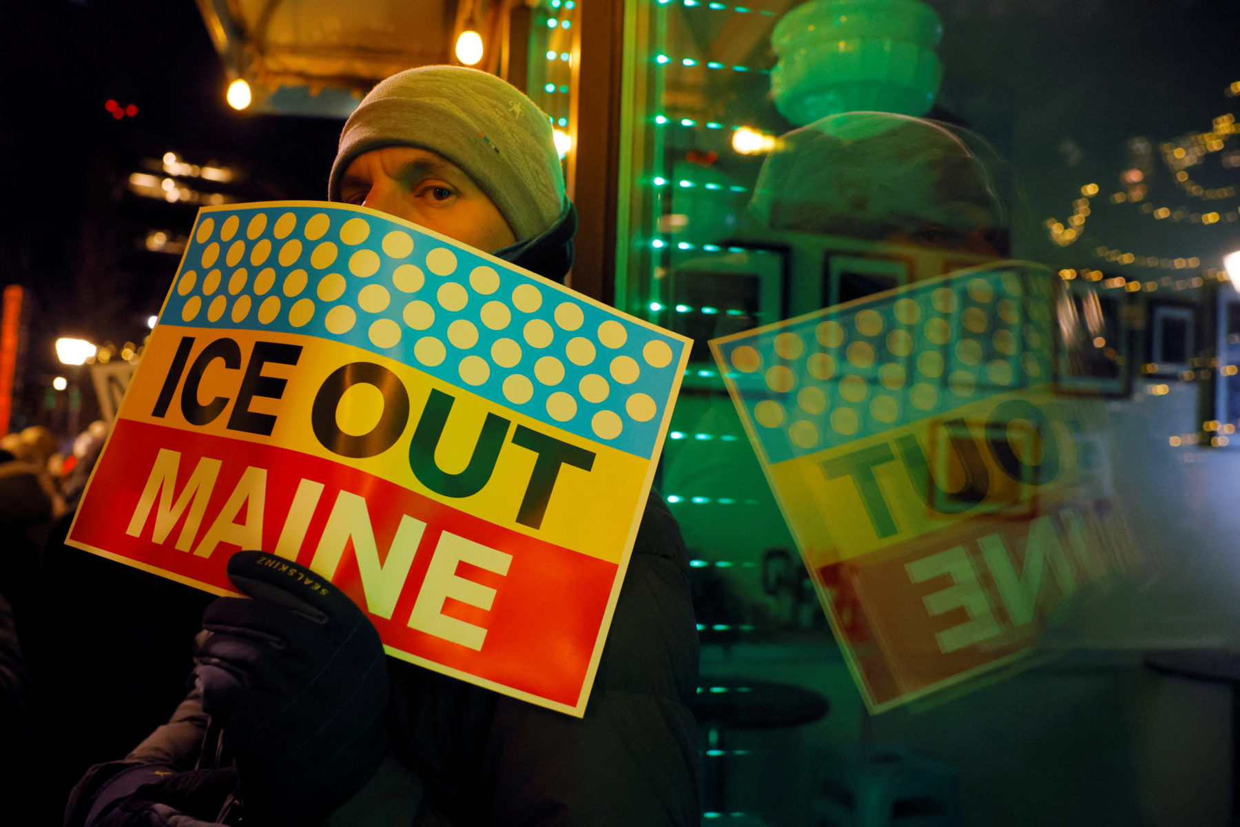 A demonstrator holds an 'ICE Out Maine' sign at a Portland protest. Brian Snyder/Reuters