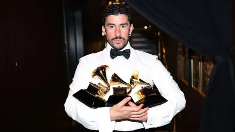 Bad Bunny holding three Grammy awards
