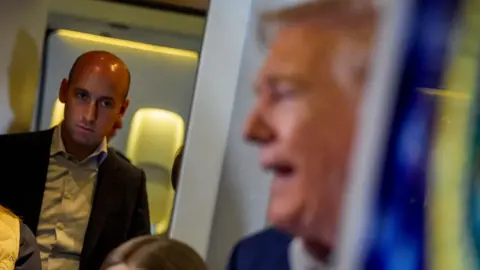 Getty Images Stephen Miller watches and listens to Trump talking to the press on board Air Force One. He is in sharp focus while Trump's face is blurred