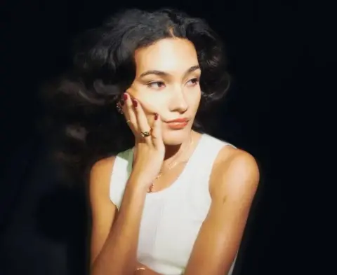 Olivia Dean performing on stage in a red dress