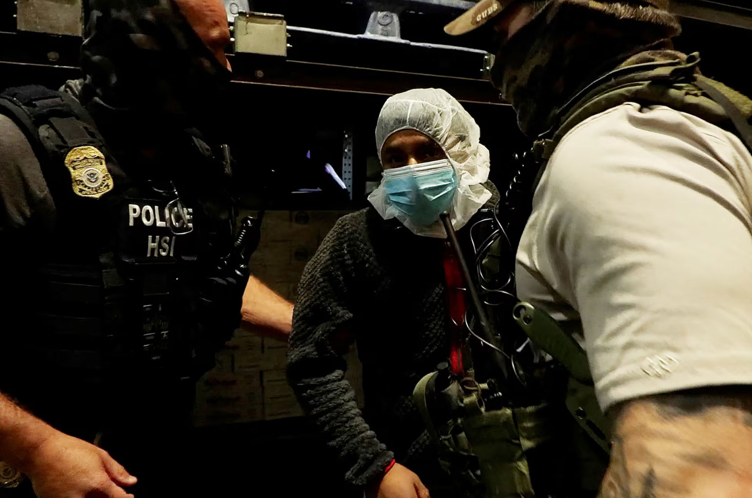 Agents in tactical gear during an immigration enforcement operation; some faces are covered