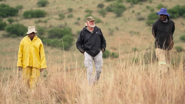 White South African farmers walk through a field during 60 Minutes reporting.