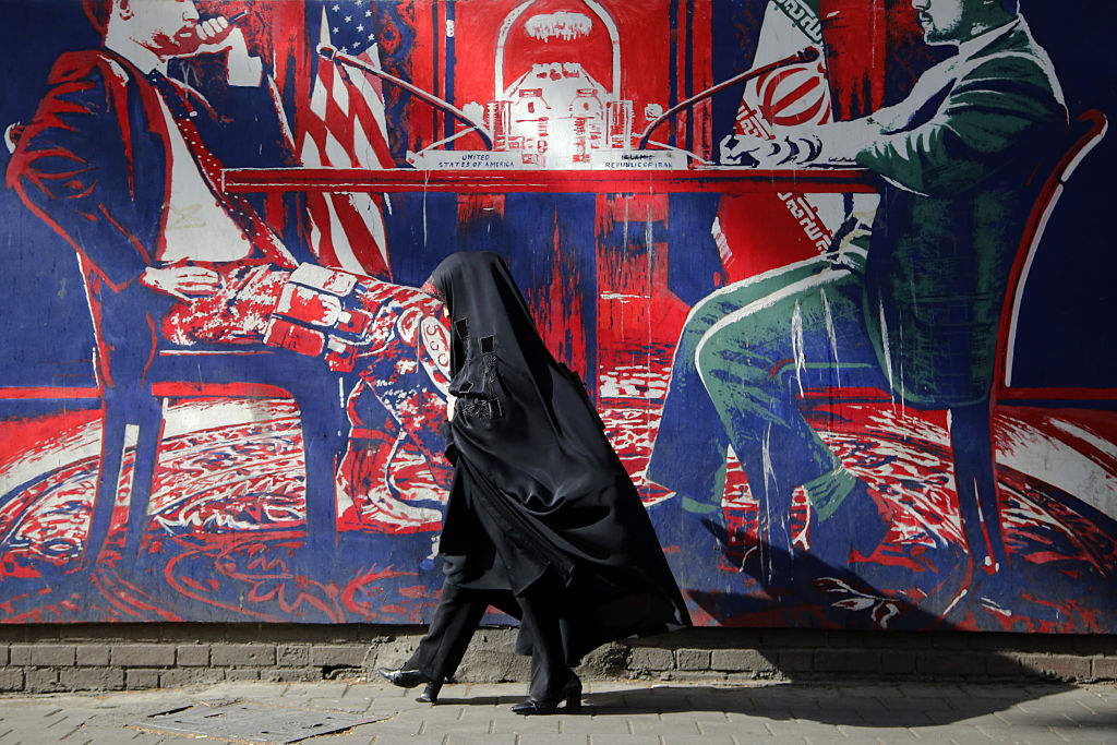 A passerby walks past a mural depicting U.S.-Iran tensions.
