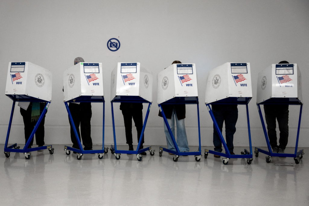 Row of voting booths with voters at a New York City polling place in 2024.