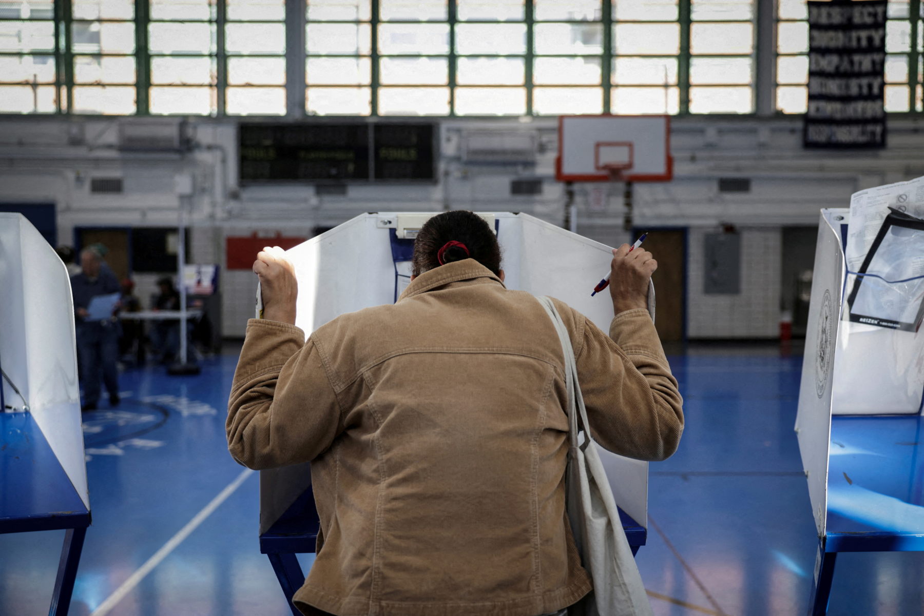 A voter stands at a privacy booth inside a gym during a U.S. election.
