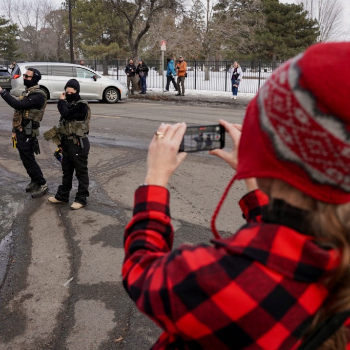 Left: A community member records with their phone as federal immigration agents conduct immigration enforcement tasks in Minneapolis, Minnesota, U.S., February 5, 2026. File photo by Seth Herald/Reuters. - pbs