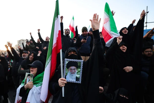 Protesters hold a framed photo and flags during a rally after reports of Khamenei's killing