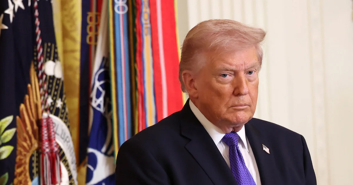 U.S. official speaking at a briefing with flags in the background
