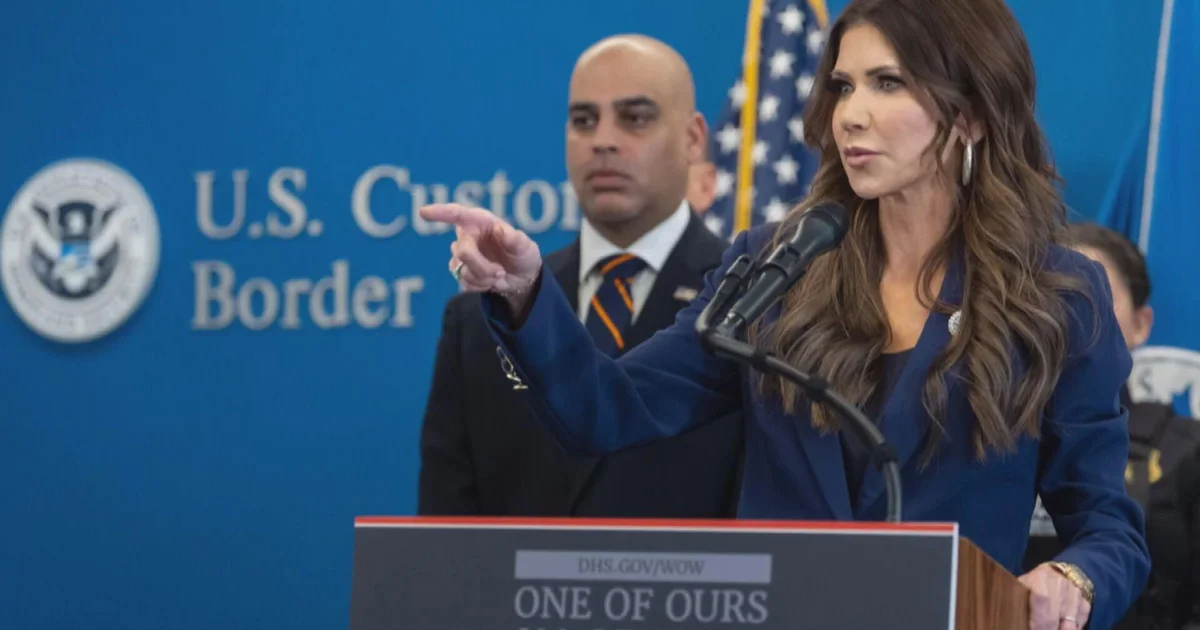 Kristi Noem at a DHS-branded podium amid internal tensions ahead of her departure from the department.