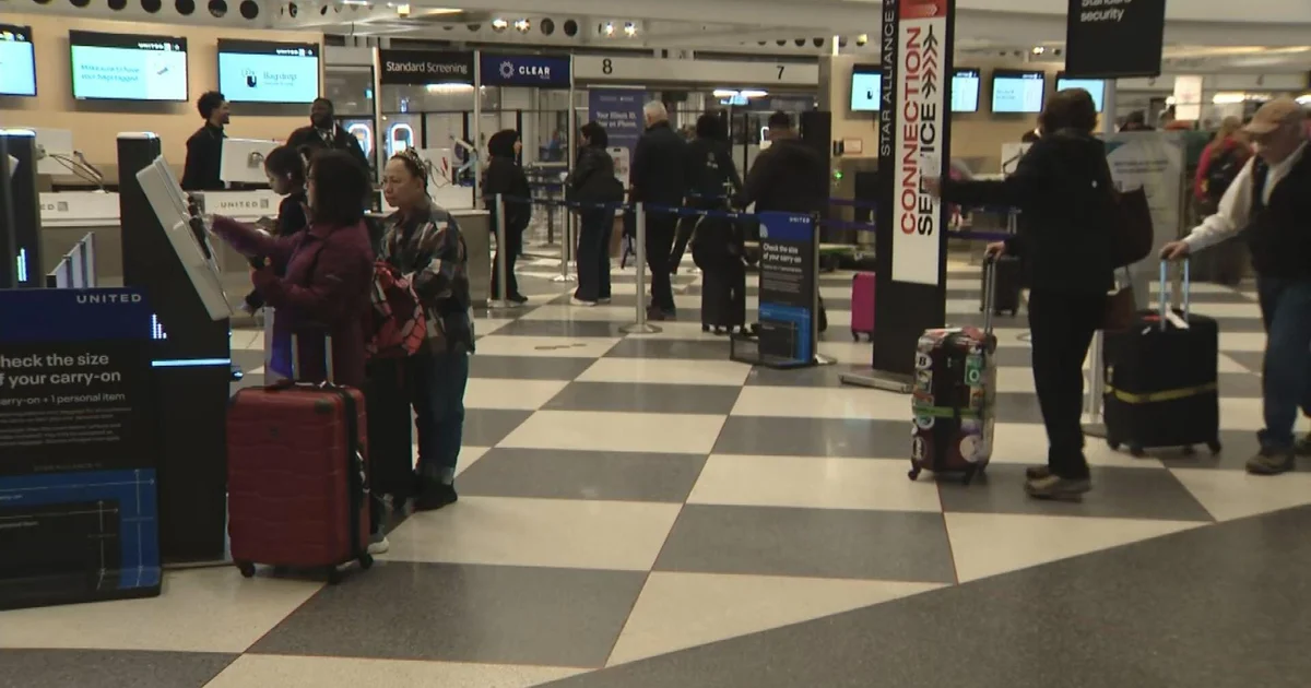Travelers queue at a TSA checkpoint during extended wait times at a major U.S. airport.