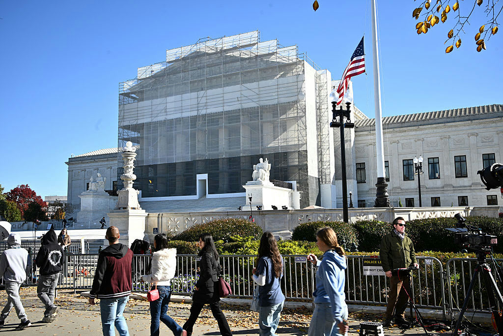 Visitors gather outside the U.S. Supreme Court with the American flag flying.