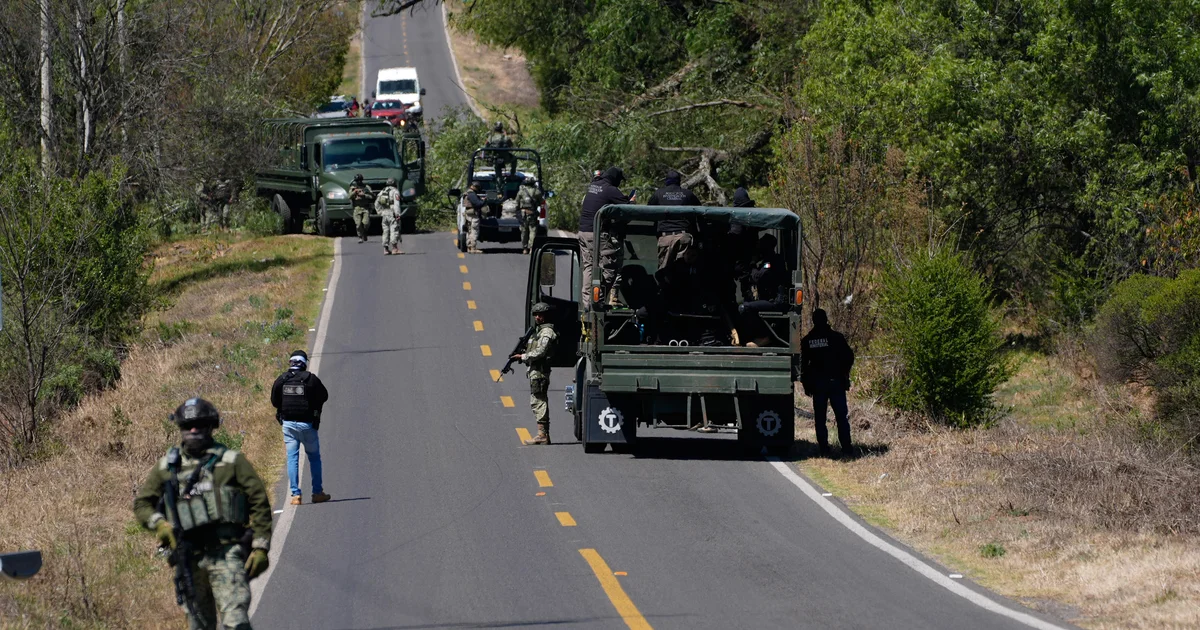 Security forces convoy and checkpoint blocking a roadway during anti-gang operations.