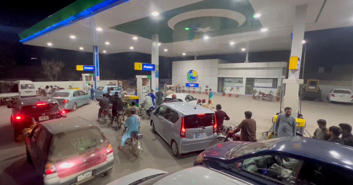 Drivers queue at a gas station, reflecting pressure on fuel prices.