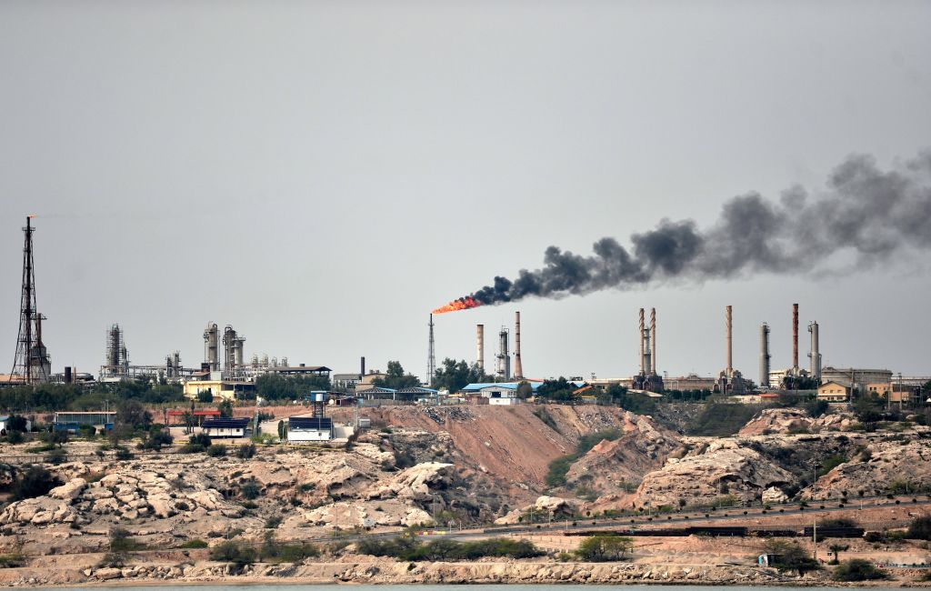 Oil refinery with flare stack and smoke plume underscoring oil supply disruptions