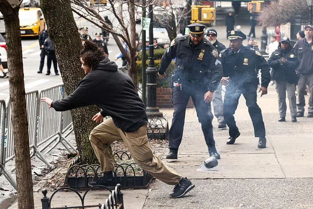 A man flees after throwing a homemade explosive device toward police during a protest organized by far-right influencer Jake Lang outside Gracie Mansion in New York City.
