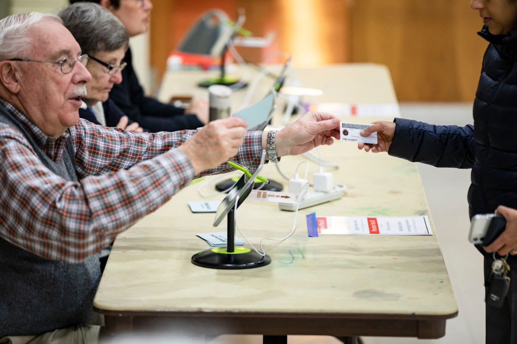 Poll worker checks a voter's photo ID at a polling station.