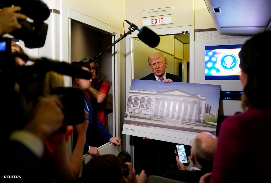 Trump holds a large design board as reporters look on, illustrating the concept tied to a White House ballroom.