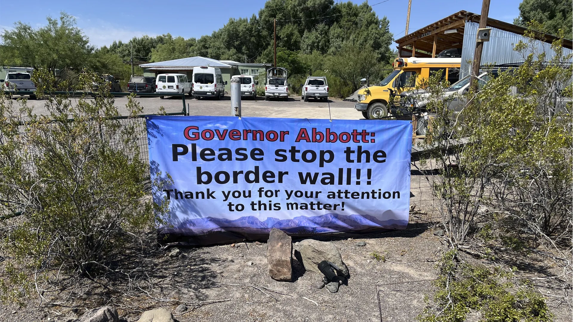 Banner reading "Governor Abbott: Please stop the border wall" hung on a fence in Presidio, Texas.